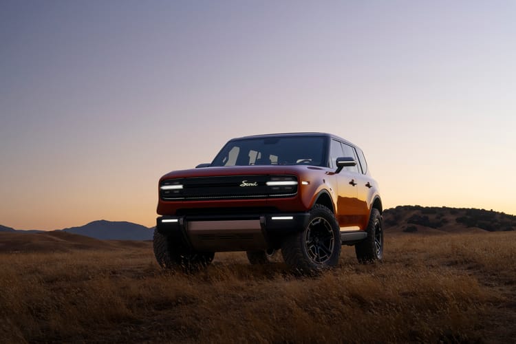 SUV parked in a grass field at sunset
